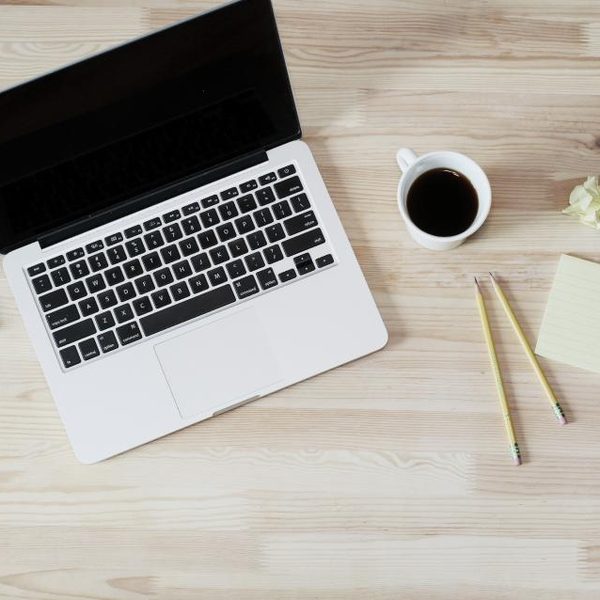 A laptop and a cup of coffee on a wooden desk